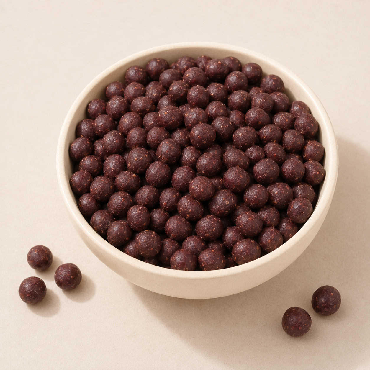 Small dark burgundy Beri Ka Ber Goli candies in a ceramic bowl